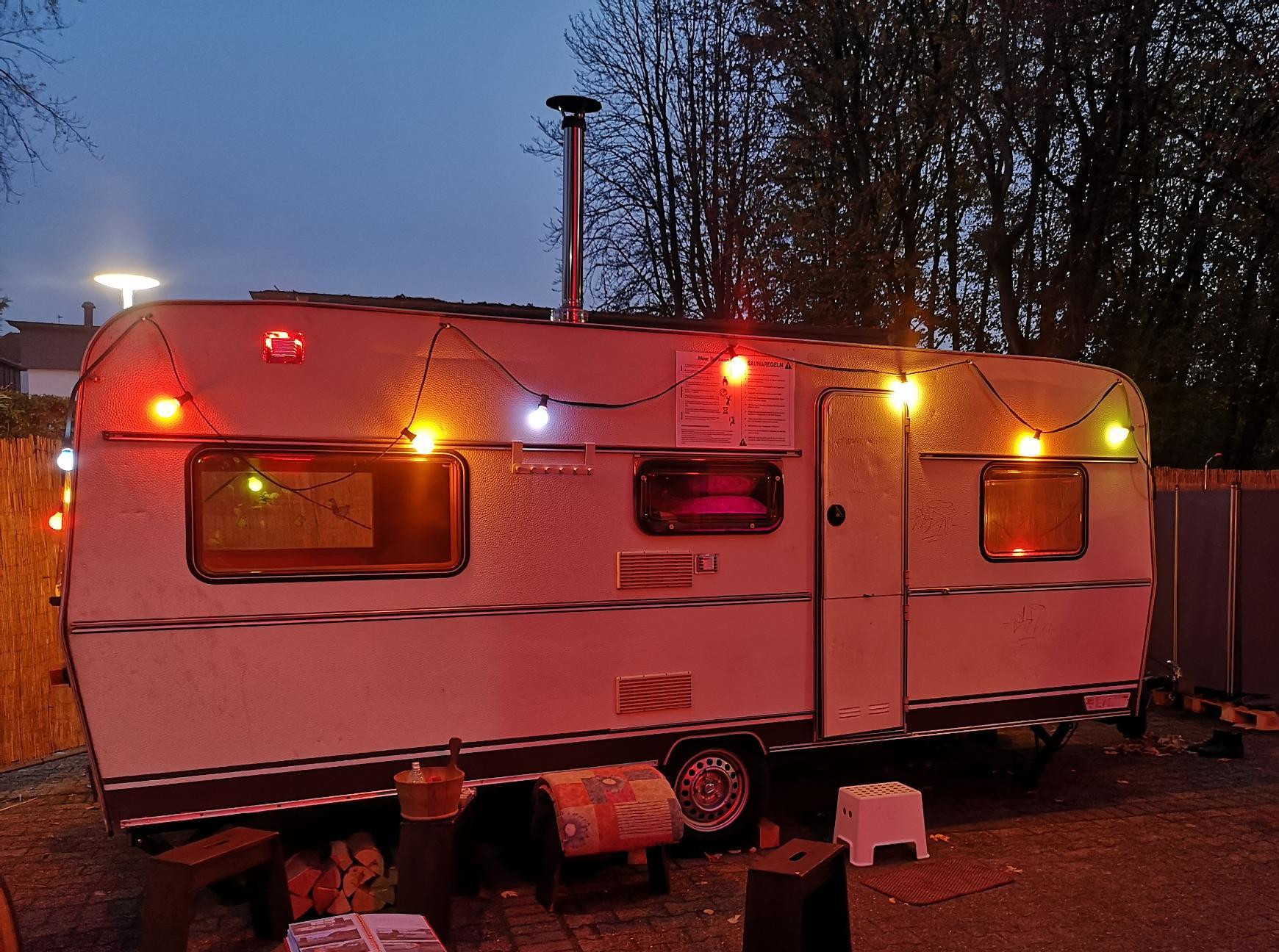 Wohnwagenanhänger mit Lichterkette in der Dämmerung 